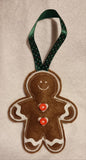 Decorative gingerbread man ornament with a green ribbon on a beige background